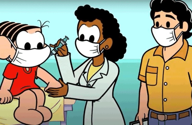 Desenho da personagem Mônica tomando vacina no braço, aplicada por uma profissional da saúde. Ao lado, o personagem que representa o pai da Mônica acompanha